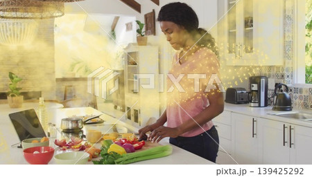 Chopping woman wearing pink tee and jeans preparing bell peppers on cutting board in home kitchen Chopping woman wearing pink tee and jeans preparing bell peppers on cutting board in home kitchen 139425292
