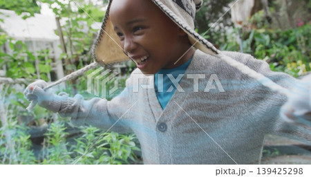 Laughing cheerful boy stretching arms wide in backyard garden, with knit hat and gloves 139425298