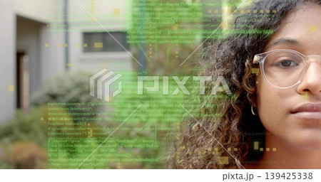 Teenager with clear-framed glasses and hoop earring analyzing code overlay in courtyard, copy space 139425338