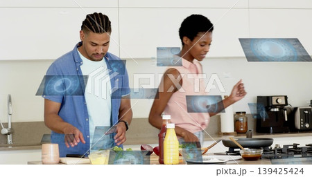 Man chopping and woman stirring in home kitchen, with vegetables on cutting board Man chopping and woman stirring in home kitchen, with vegetables on cutting board 139425424