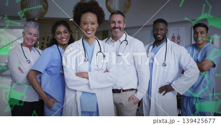Standing team in clinic hall with scrubs and coats, stethoscopes, charts, lights and green overlays Standing team in clinic hall with scrubs and coats, stethoscopes, charts, lights and green overlays 139425677