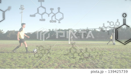 Dribbling player in yellow jersey on grass field with goal net, chemical diagrams, copy space Dribbling player in yellow jersey on grass field with goal net, chemical diagrams, copy space 139425739