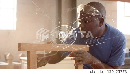 Mature carpenter in safety goggles sanding stool in workshop, showing bank graphics, copy space Mature carpenter in safety goggles sanding stool in workshop, showing bank graphics, copy space 139425778