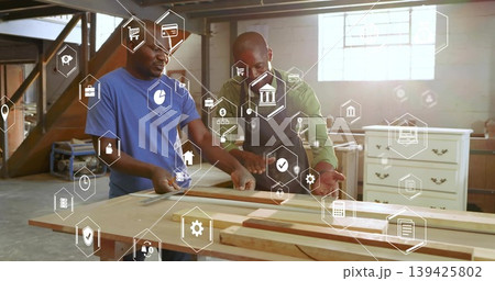 Two mature carpenters aligning wooden board in woodshop, with tape measure, ruler and digital icons Two mature carpenters aligning wooden board in woodshop, with tape measure, ruler and digital icons 139425802