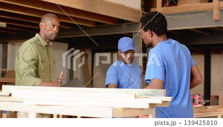 Directing man wearing olive shirt holding clipboard at carpentry workbench with planks, copy space Directing man wearing olive shirt holding clipboard at carpentry workbench with planks, copy space 139425810