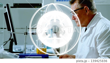 Observing chemist studying monitor at lab bench with flask on clamp stand, pipette rack, copy space Observing chemist studying monitor at lab bench with flask on clamp stand, pipette rack, copy space 139425836