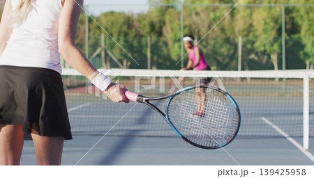 Woman in white top, black skirt swinging racket on blue court, with net, lines, copy space Woman in white top, black skirt swinging racket on blue court, with net, lines, copy space 139425958