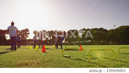 Adjusting female soccer players wearing white shirts black shorts on club pitch, cones hurdles Adjusting female soccer players wearing white shirts black shorts on club pitch, cones hurdles 139426001