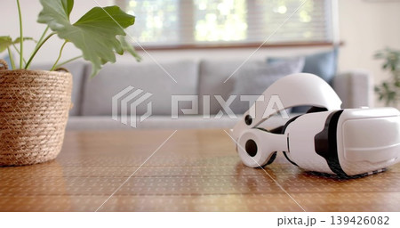 Resting white VR-headset on wood table in lounge, showing woven basket and binary motif, copy space 139426082