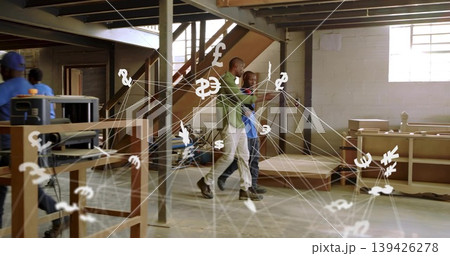 Walking two carpenters in green and blue shirts across shop, with wood planer and currency overlay Walking two carpenters in green and blue shirts across shop, with wood planer and currency overlay 139426278