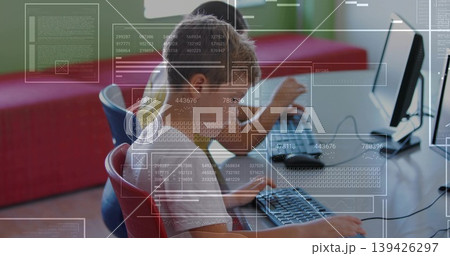Working elementary students typing code on desktop monitors in coding lab, with digital overlays Working elementary students typing code on desktop monitors in coding lab, with digital overlays 139426297