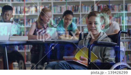 Smiling child boy in wheelchair reading open yellow book at study table in library, copy space 139426299