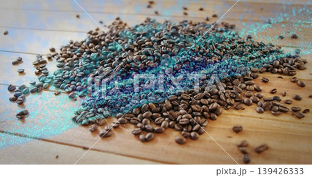 Displaying roasted coffee beans scattering across wooden tabletop, with turquoise digital artifacts Displaying roasted coffee beans scattering across wooden tabletop, with turquoise digital artifacts 139426333