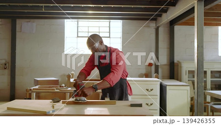 Sanding mature carpenter wearing apron smoothing wooden plank at carpentry shop, sander, lumber 139426355