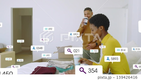 Sorting clothes couple standing beside bed in bedroom, with coffee cups, boxes, icons, copy space Sorting clothes couple standing beside bed in bedroom, with coffee cups, boxes, icons, copy space 139426416