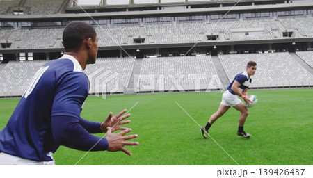 Preparing player wearing navy jersey padded vest on stadium pitch, rugby ball, copy space Preparing player wearing navy jersey padded vest on stadium pitch, rugby ball, copy space 139426437