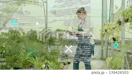 Holding tablet, horticultural workers monitoring potted plants in greenhouse, with data overlay 139426503