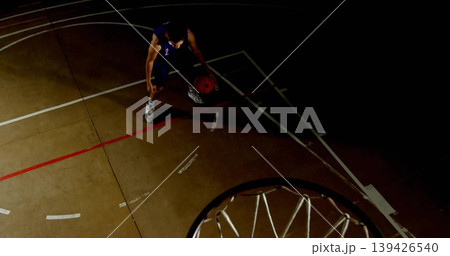 Dribbling male player wearing dark number 2 jersey on gym court, red basketball, rim, painted lines 139426540