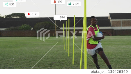 Running teen in neon bib holding white-blue ball on pitch, with yellow poles overlays, copy space 139426549