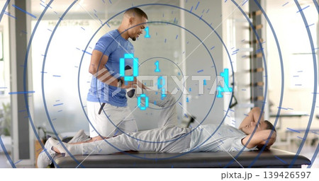 Kneeling coach in blue tee white-shorts guiding client on padded table in studio with AR data 139426597