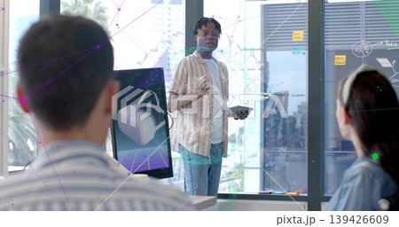 Standing man holding tablet and gesturing in modern office, VR monitor, glass board, striped shirt 139426609
