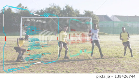 Standing soccer players wearing jerseys analyzing digital overlay on park pitch, with goal net 139426744