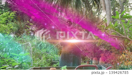 Standing Black gardener inspecting clay pot at bench in tropical garden, with teal light streaks 139426785