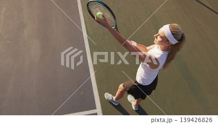 Tossing tennis ball holding racket athlete in sportswear serving on hard court, copy space Tossing tennis ball holding racket athlete in sportswear serving on hard court, copy space 139426826