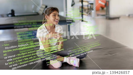 Sitting girl clasping hands on black mat in gym, wearing striped tee, pink shoes, code overlay Sitting girl clasping hands on black mat in gym, wearing striped tee, pink shoes, code overlay 139426857
