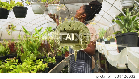 Inspecting woman wearing striped apron checking hanging white planter at nursery bench, AI overlay 139426932