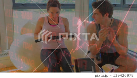 Rowing woman in sportswear, trainer cheering in gym with rower exercise ball and red chart overlay Rowing woman in sportswear, trainer cheering in gym with rower exercise ball and red chart overlay 139426979