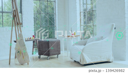 Sitting white slipcovered armchair offering cozy seating in bright art corner, with paint jars Sitting white slipcovered armchair offering cozy seating in bright art corner, with paint jars 139426982