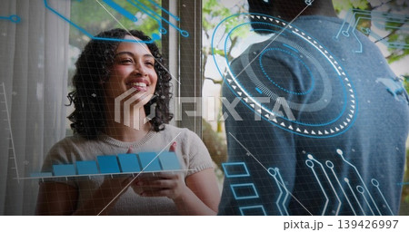 Presenting woman at left holding tablet with blocks by window wearing knit top, AR, copy space Presenting woman at left holding tablet with blocks by window wearing knit top, AR, copy space 139426997