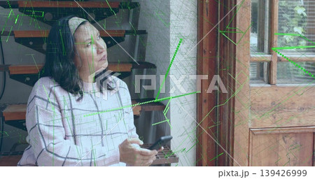 Holding smartphone, mature woman gazing toward light by wooden doorway, in checked sweater, overlay Holding smartphone, mature woman gazing toward light by wooden doorway, in checked sweater, overlay 139426999
