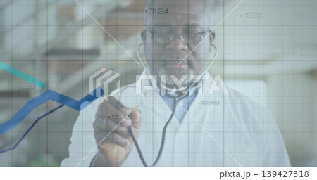 Senior doctor in lab coat, surgical cap holding stethoscope toward camera in clinic, data overlay 139427318