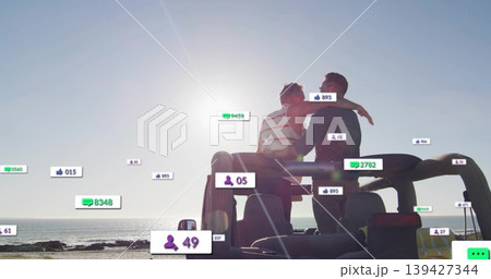 Sitting two men in striped tank embracing, watching horizon on SUV rear at beach, floating icons Sitting two men in striped tank embracing, watching horizon on SUV rear at beach, floating icons 139427344