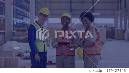 Standing three workers wearing safety vests, hard hats in aisle with pallet racks, holding tablet Standing three workers wearing safety vests, hard hats in aisle with pallet racks, holding tablet 139427346