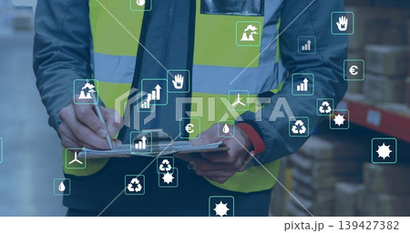 Inspecting worker in yellow vest noting clipboard with pen in warehouse racks, showing AR icons Inspecting worker in yellow vest noting clipboard with pen in warehouse racks, showing AR icons 139427382