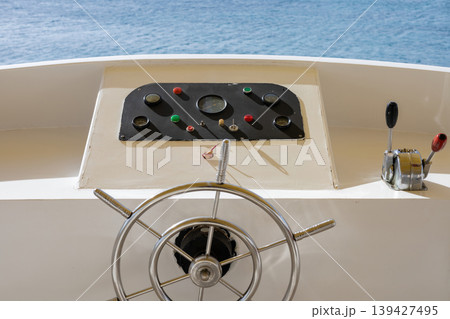Nautical steering wheel on boat overlooking blue ocean for marine navigation concept Nautical steering wheel on boat overlooking blue ocean for marine navigation concept 139427495