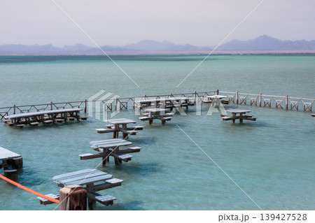 Tranquil lakeside setting with wooden picnic tables surrounded by serene waters and distant mountain views 139427528