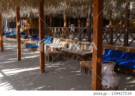 Tranquil outdoor lounge with wooden canopy and rustic seating 139427534