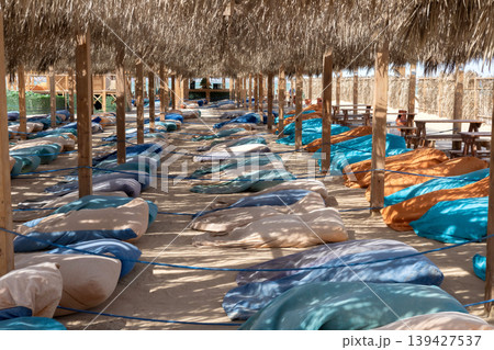 Relaxing outdoor seating area under thatched roof with colorful cushions 139427537