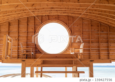 Cozy oceanside retreat with wooden interior and scenic views through circular window 139427556