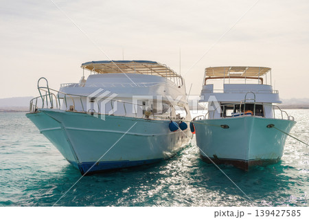 Twin boats anchored on serene blue waters in a calm coastal setting Twin boats anchored on serene blue waters in a calm coastal setting 139427585