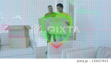 Carrying two adults in yellow tops lifting large cardboard box in living room, security overlay 139427653