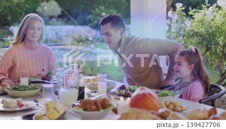 Gathering family sitting at table on porch, pink-sweater woman, man leaning, roast-chicken Gathering family sitting at table on porch, pink-sweater woman, man leaning, roast-chicken 139427706
