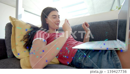 Reclining woman wearing red tee and denim shorts watching laptop on lap under skylight, neon specks Reclining woman wearing red tee and denim shorts watching laptop on lap under skylight, neon specks 139427736
