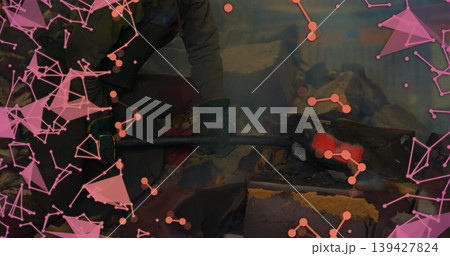 Wielding tongs smith in jacket and gloves forging glowing billet at forge, with pink orange mesh Wielding tongs smith in jacket and gloves forging glowing billet at forge, with pink orange mesh 139427824