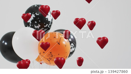 Floating Halloween balloon cluster in gray studio, showing skull prints, red hearts, copy space 139427860