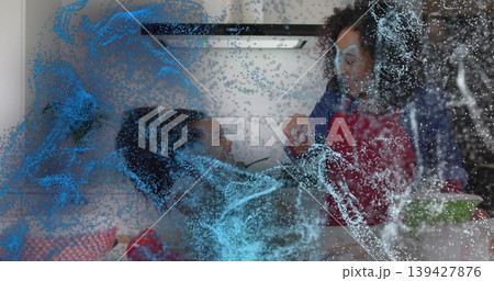 Handing small item, mother leaning toward girl at kitchen counter, wearing red apron, blue overlay Handing small item, mother leaning toward girl at kitchen counter, wearing red apron, blue overlay 139427876